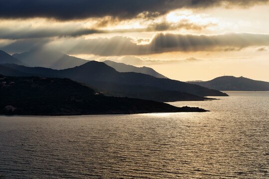 Coastline backlit, sun rays through clouds, L'Ile-Rousse, Ile Rousse, Haute-Corse, Balagne, North Coast, Corsica, France, Europe
