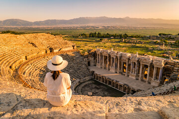 Hierapolis ancient city Pamukkale Turkey, a young woman with a hat watching the sunset by the ruins...