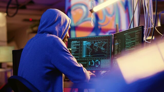 African american hooded hacker hiding in underground base, anxiously looking around for threats, feeling nervous after stealing data from victims using virus, trying hard to evade law enforcement