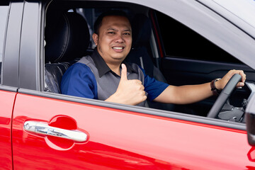 Young handsome smiling Asian man getting a new car and showing thumbs up. Buy or rent a car concept