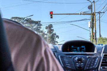 View from behind a car, of a red light, a camera and street lighting cables.