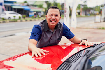 Excited young handsome Asian man getting the new car. He hugged his car and was very happy. Buy or...