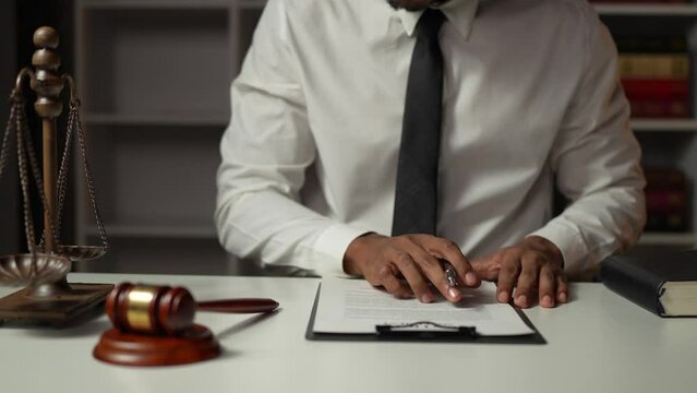 Asian male lawyer or lawyer using pen to check business information and details. Business venture acknowledgment signing documents at the desk in he office.	