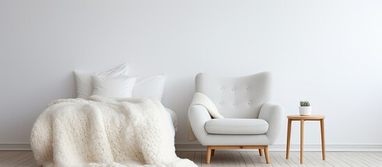 Stylish and cozy Scandinavian interior featuring a hand knitted merino wool chunky blanket, with a bed, chair, and white wall. - obrazy, fototapety, plakaty