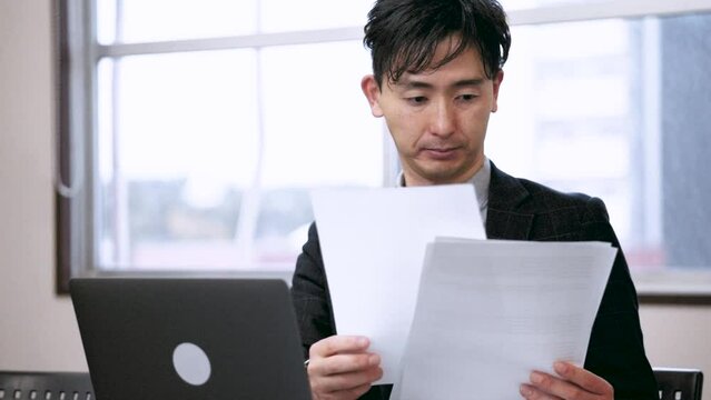 ノートパソコンを使って資料を作成する男性ビジネスマン