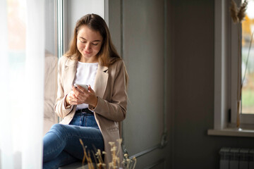 Work-life-balance, businesswoman on the windowsill in the hall with smartphone