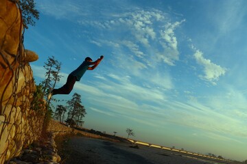 man jumping from the embarkment in the aie in assam - obrazy, fototapety, plakaty
