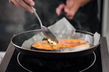 Man cooking salmon steak roasting on parchment with butter