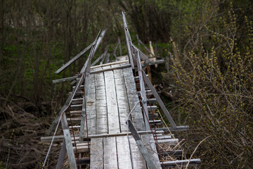 A wooden suspension bridge in the countryside distorted after a spring flood