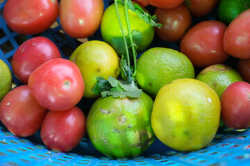 Red tomatoes and green lemon in the blue basket.