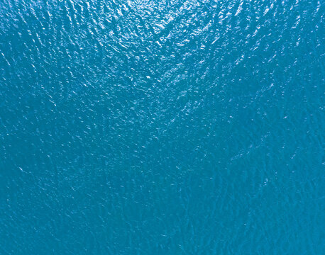 Aerial view of a crystal clear sea water texture. View from above Natural blue background. Blue water reflection. Blue ocean wave. Summer sea. Drone. Top view