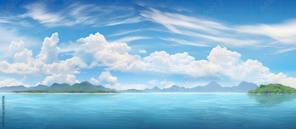 Sticker Tropical sea with islands on the horizon and fluffy clouds