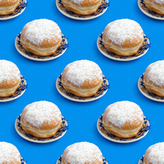 Seamless pattern with traditional Hanukkah doughnut Sufganiyah for Jewish holiday on blue background.