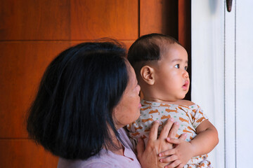 An Asian woman is playing with her baby boy; serious, curious expression