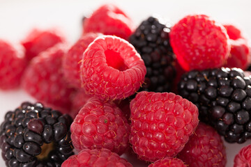 Handful of raspberry and blackberry berries on white background