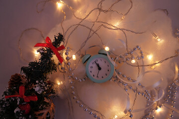 Blue retro alarm clock and a small Christmas tree on a white background
