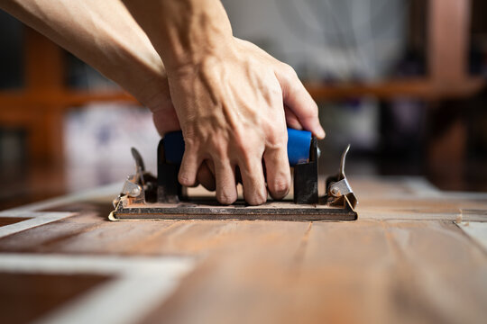 Sanding wooden floor with sandpaper holder