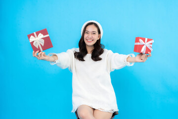 Asian woman with long hair smile happily Hand the gift box to the front. Waiting to prepare for the New Year and Christmas celebrations, taking pictures of the blue scene in the studio.