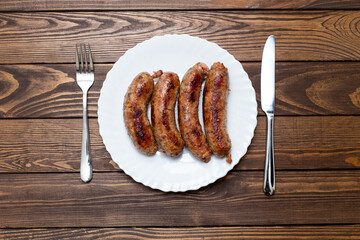 lunch.cutlery plate, fork and knife. fried sausages on a plate. grilled homemade sausages with herbs top view