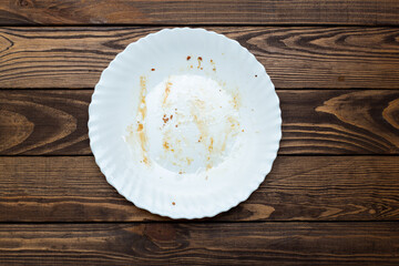 dirty plate on the table. leftovers from lunch. greasy, unwashed dishes