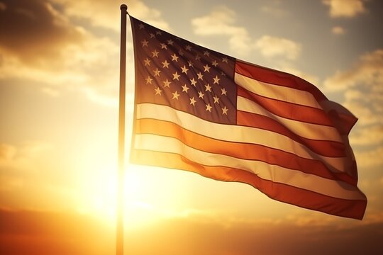 An inspiring image of the American flag waving proudly against a backdrop of a warm sunset sky. The sun's rays peeking around the flag create a radiant silhouette, highlighting the stars and stripes