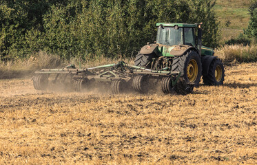 A tractor plows the soil in a field