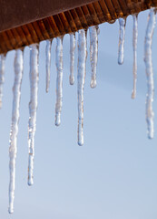 Icicles hang from the roof against the blue sky