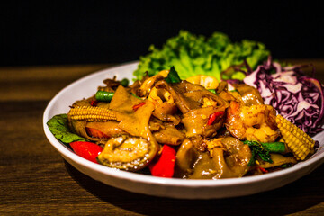 Flat Rice noodles stir-fried spicy with prawns, squid, mushrooms and Thai Basil