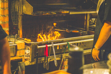 chef grilling at open fire wood grill in a open kitchen restaurant
