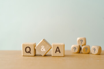 Q and A text , an abbreviation of question and answer, and blurred question mark on wooden cube block - obrazy, fototapety, plakaty