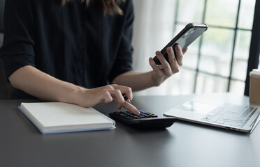 Fototapeta premium Happy businesswoman using a smartphone and sitting at desk in office.