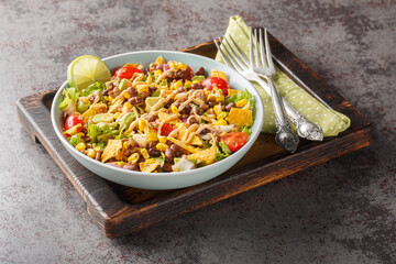 Easy taco salad is made with seasoned ground beef, crisp lettuce, vegetables, cheese and flavorful toppings closeup on the plate on the table. Horizontal - Powered by Adobe