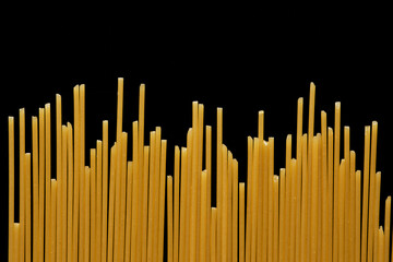 Abstract food background of dry spaghetti pasta on black, copy space