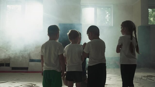 Children listen to trainer in martial arts club. Little fighting students with careful instructor prepare for exercising in gym slow motion. Kids group