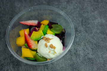 Yogurt with many fruits in a plastic cup to go. The fruit fruit such as strawberries, grapes, kiwi and mango put fresh yogurt.