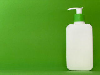 White cosmetic bottle on green background. Skin care product