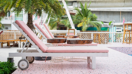 Picture of 3 sunbeds by the pool. These sunbeds by the pool are white. Covered with 2 pink mattress...