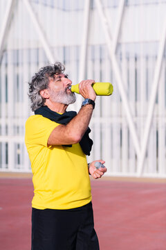 vertical photo of a senior sports man drinking water during training, concept of healthy and active lifestyle in middle age, copy space for text