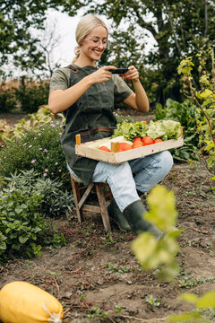 Woman taking photos of her organic garden products for sale.