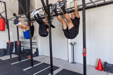 Fitness group hanging on the bar doing ab exercises in the industrial gym