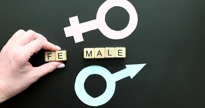 Hand changing letters in word female to male near gender symbol closeup 4k movie slow motion. Sex change concept