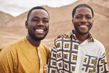 Portrait of two smiling African American men wearing traditional clothing and looking at camera...