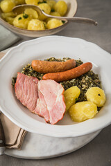 Oldenburger Gr&uuml;nkohl mit ger&auml;ucherter Kohlwurst, Pinkel, Kassler Nacken, Kartoffeln, Senf, Petersilie auf Teller und hell grau Stein Hintergrund