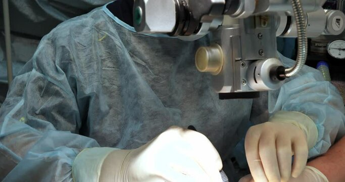 A veterinary surgeon performs surgery on a pet's eyes in a veterinary clinic. An ophthalmologist performs microsurgery on a pet's eye under a special microscope.