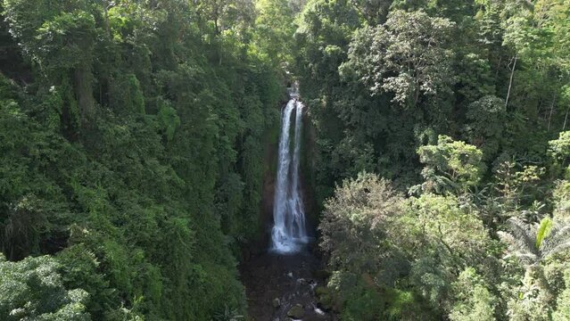 Gitgit waterfall with jungle surroundings on a sunny day in Bali, Indonesia. Aerial.
