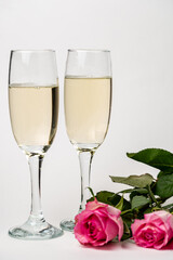 two glasses of champagne an roses on the white background