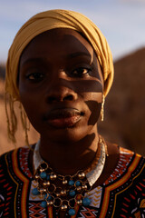Closeup portrait of young Black woman wearing traditional dress with headscarf and facing camera in...