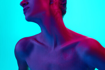 Cropped image of female neck and collarbones against blue background in neon light. Model posing...