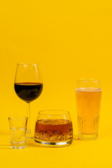 glasses filled with different types of alcohol, beer, wine, whiskey, vodka in glasses on a yellow background