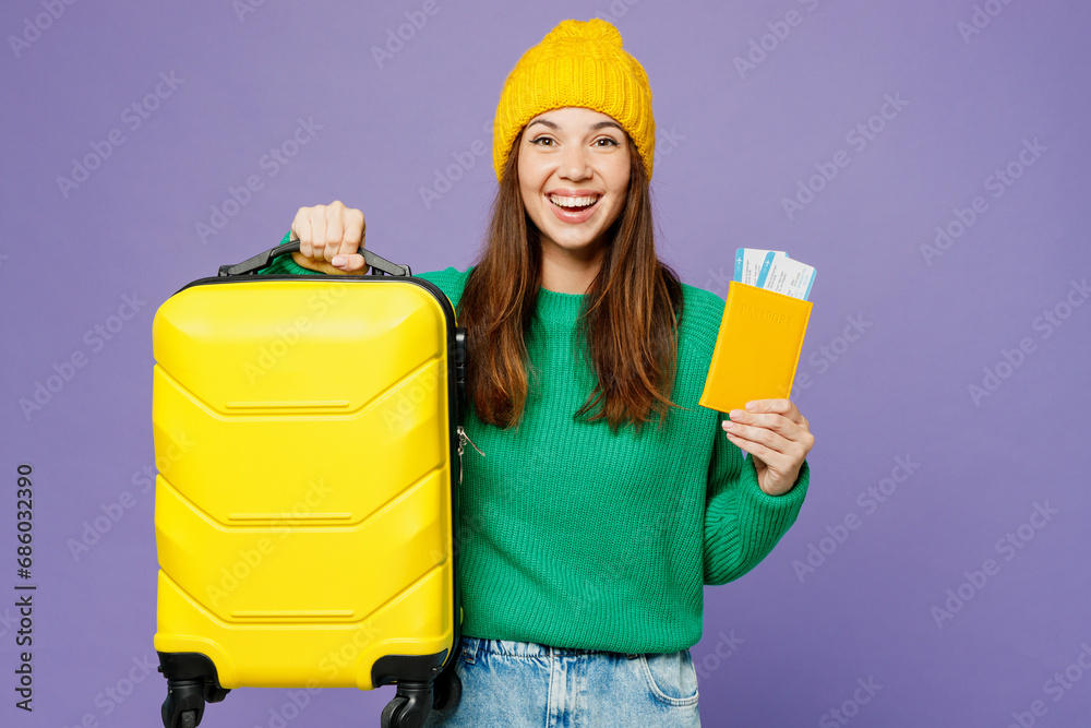 Wall mural Traveler happy woman wearing green casual clothes hold passport ticket bag isolated on plain purple background. Tourist travel abroad in free spare time rest getaway. Air flight trip journey concept.